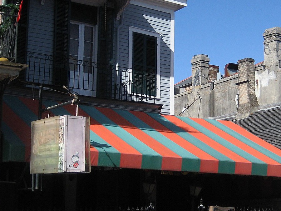 A red and green striped awning over a restaurant terrace on Bourbon Street